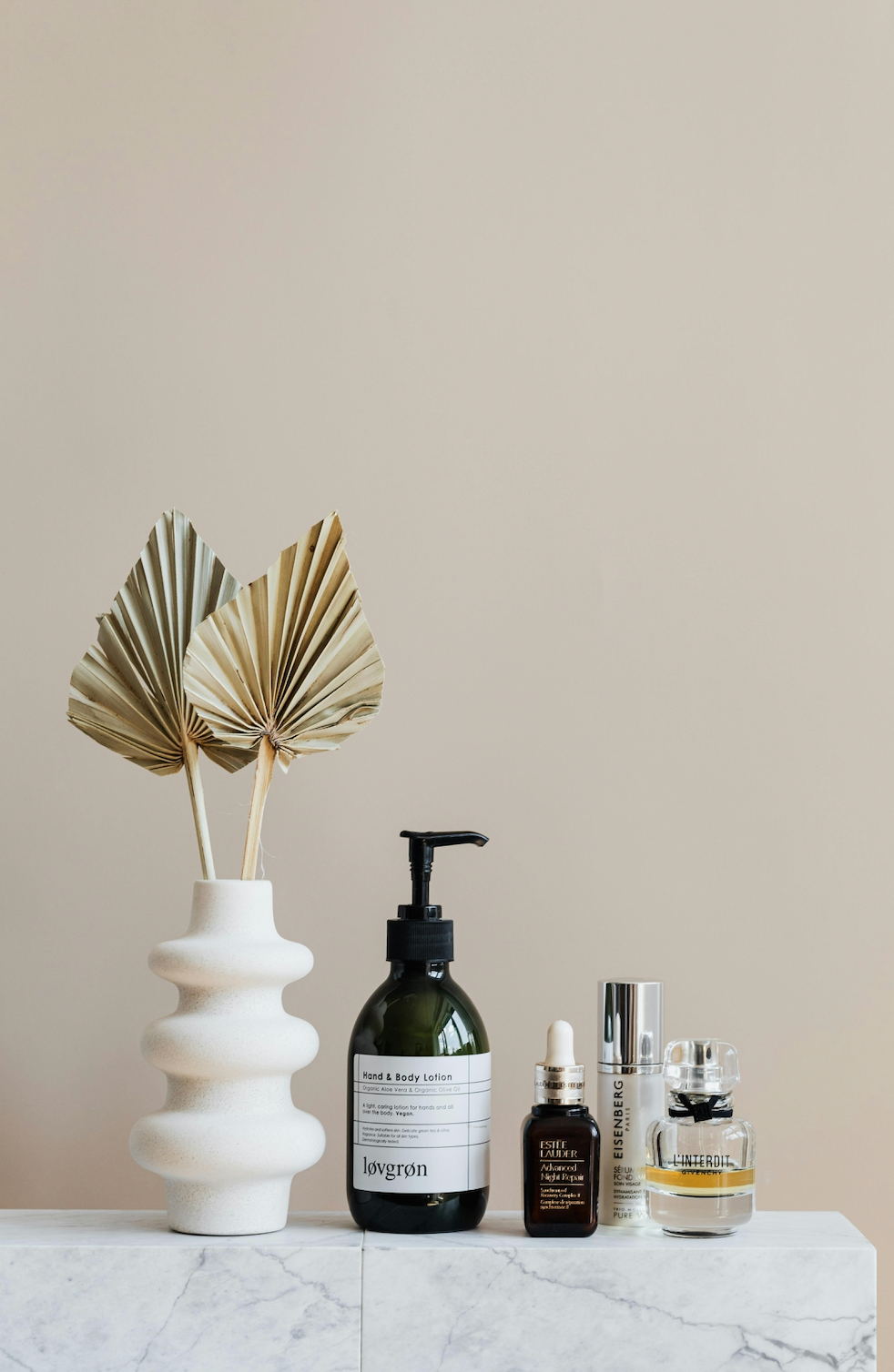 selection of skincare products next to a pretty vase for aesthetic in beige background
