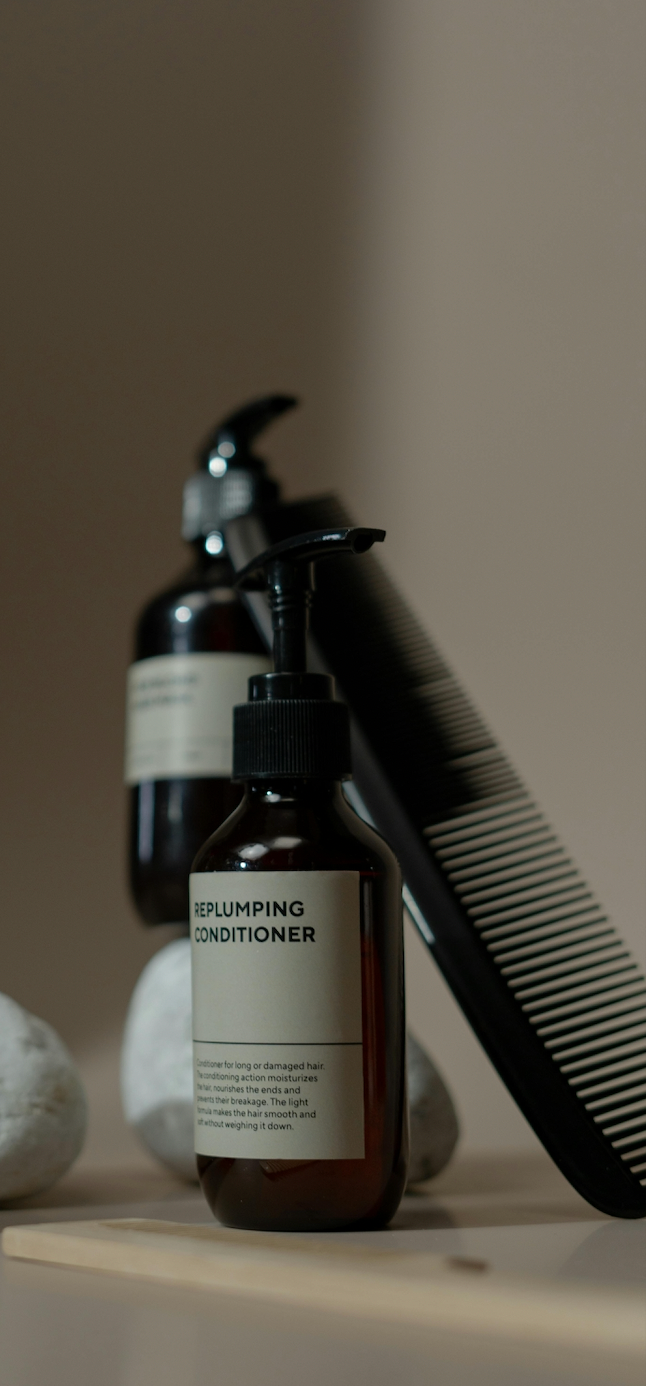 selection of haircare products  and comb in a blurred aesthetic dark beige background