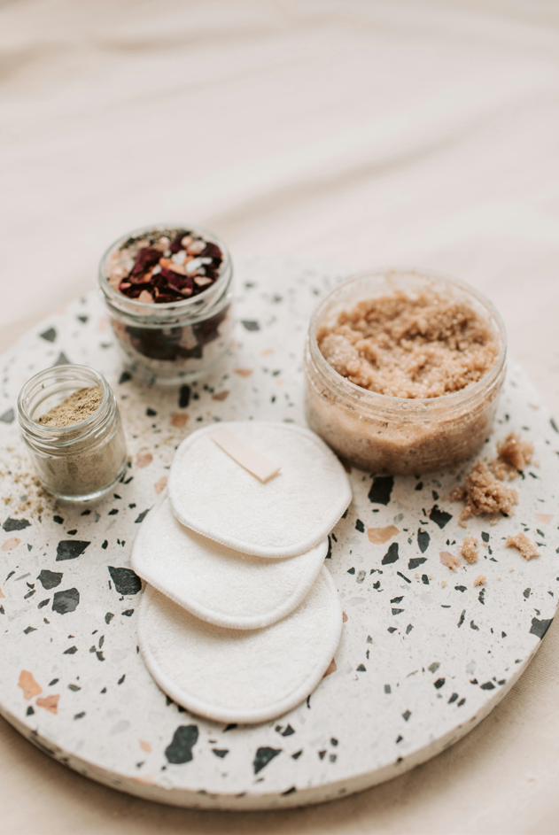 three reusable eco makeup remover pads on an aesthetic board for visual appeal with a few lip scrubs for colour contrast