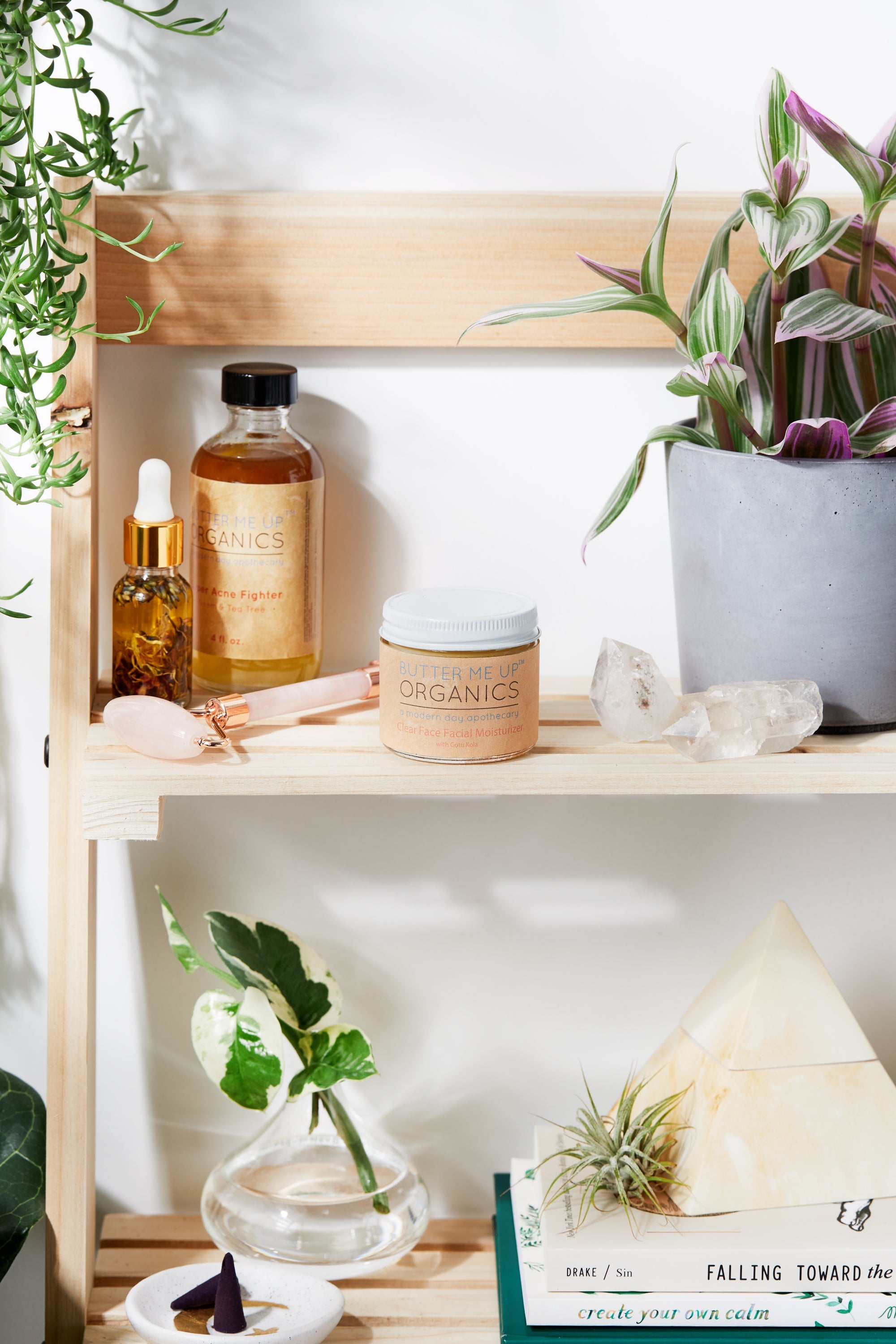 Organic Hydrating Facial Moisturizer with Aloe & Rosehip Oil closed/lidded product image in aesthetic shelf backdrop with rose quartz and green leaves, crystals and books zoomed out photo angle
