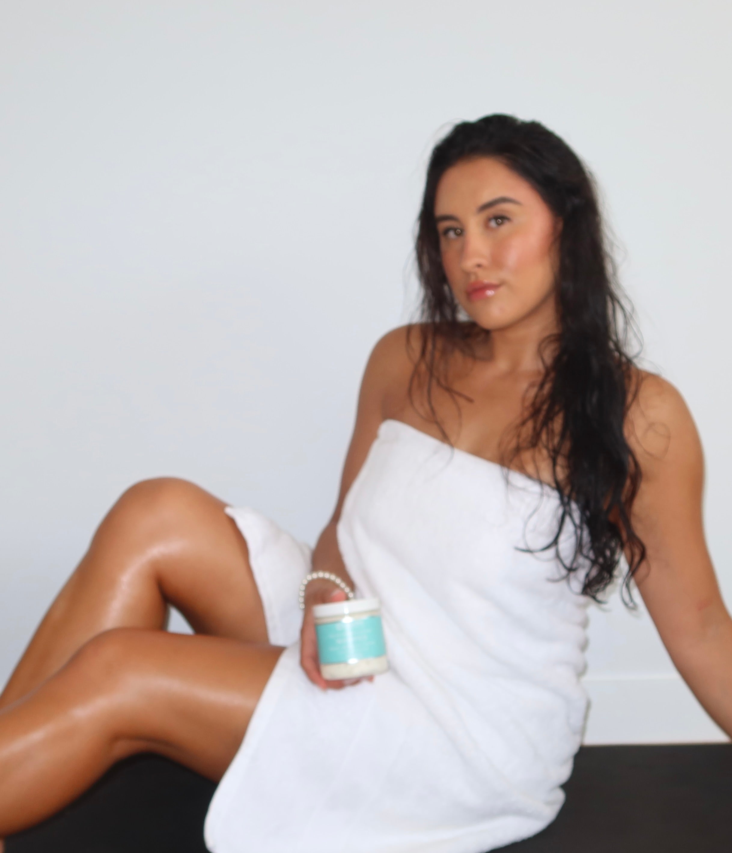 tanned model in white towel showcasing whipped body butter