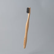 eco friendly bamboo toothbrush with charcoal bristles in white background