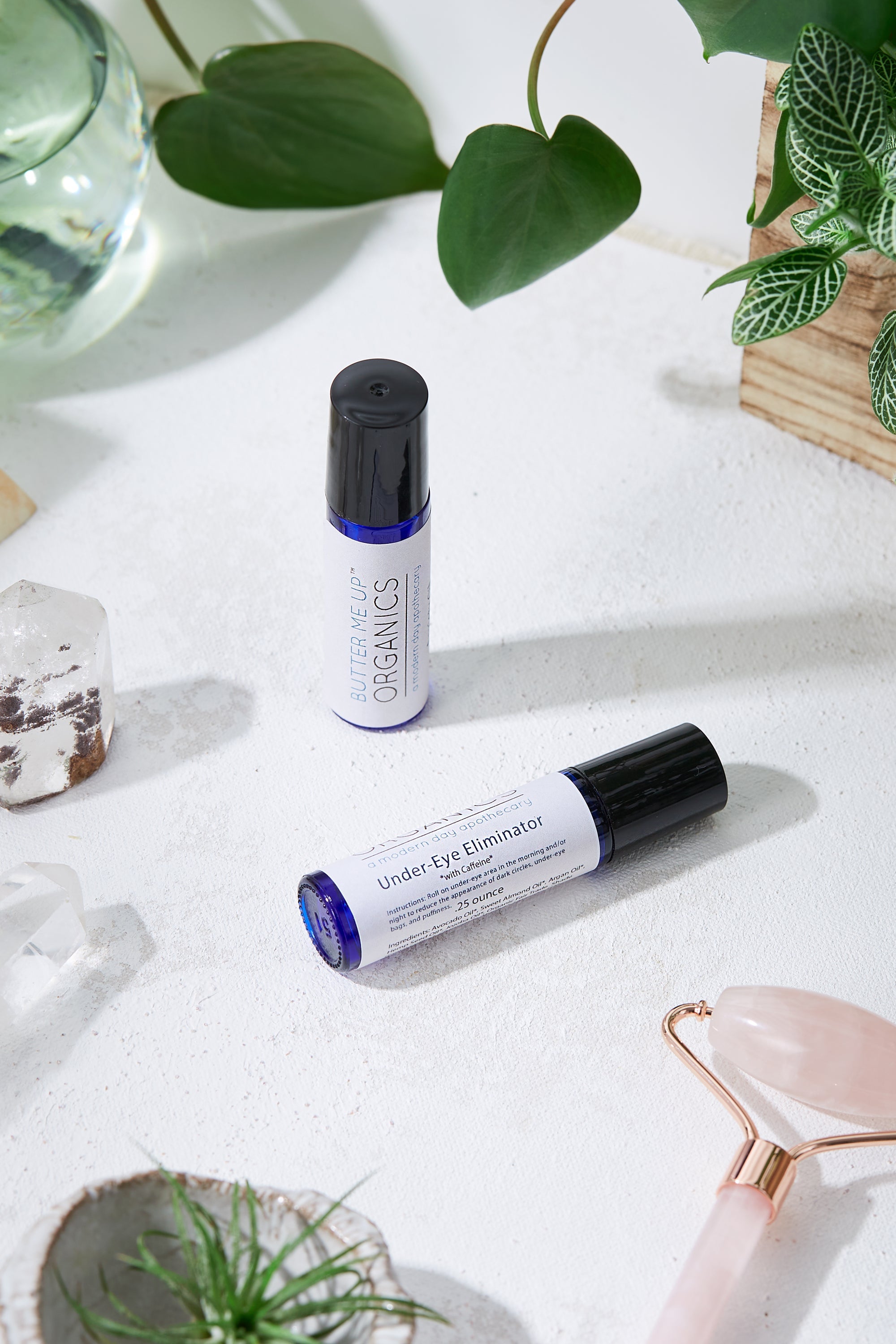 product image of Organic Caffeine Eye Repair Serum in aesthetic white backdrop with green leaves and rose quartz