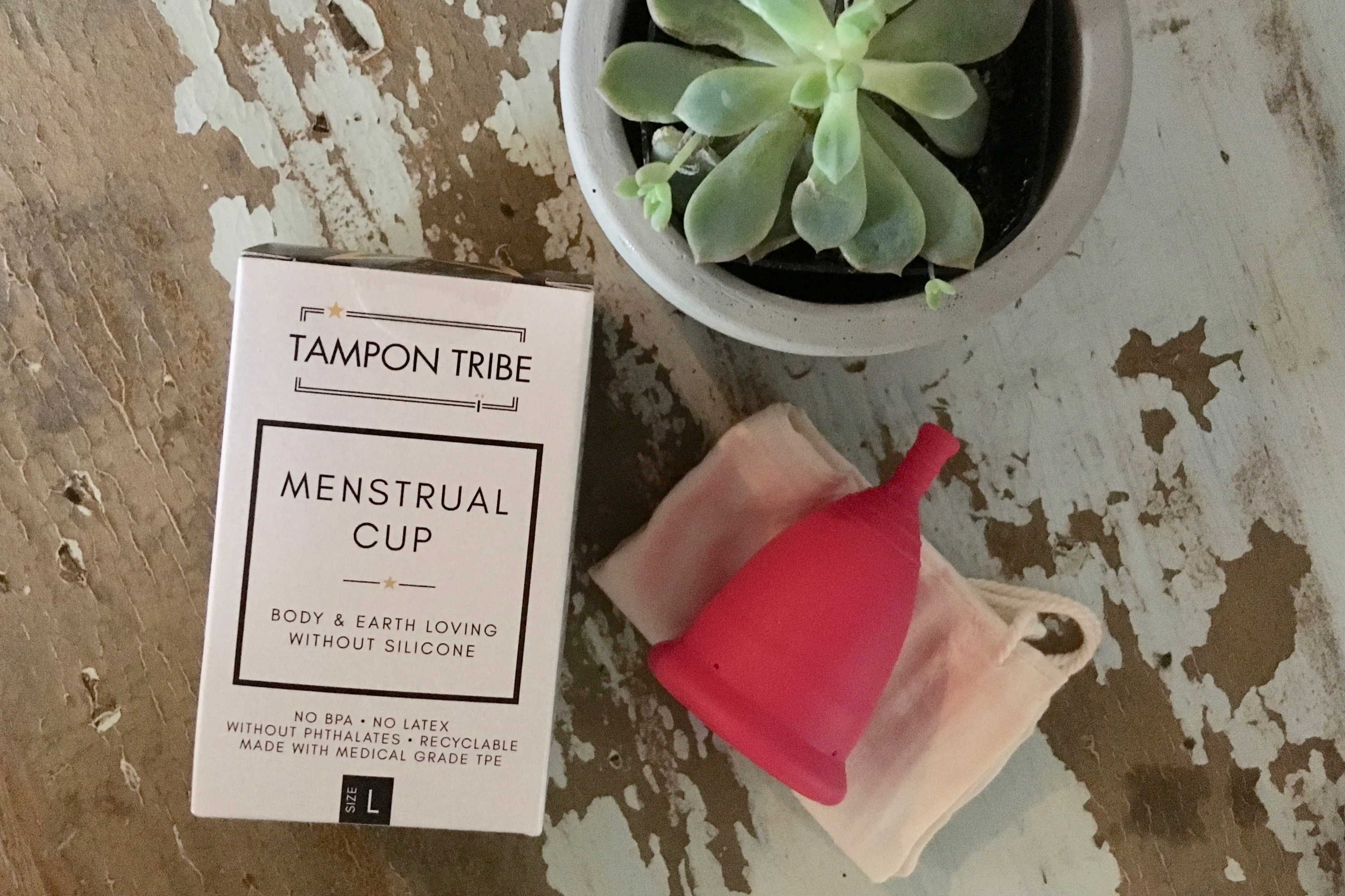 birds eye view shot of Pink Vegan & Silicone-Free Menstrual Cup alongside the white boxed packaging it comes in 