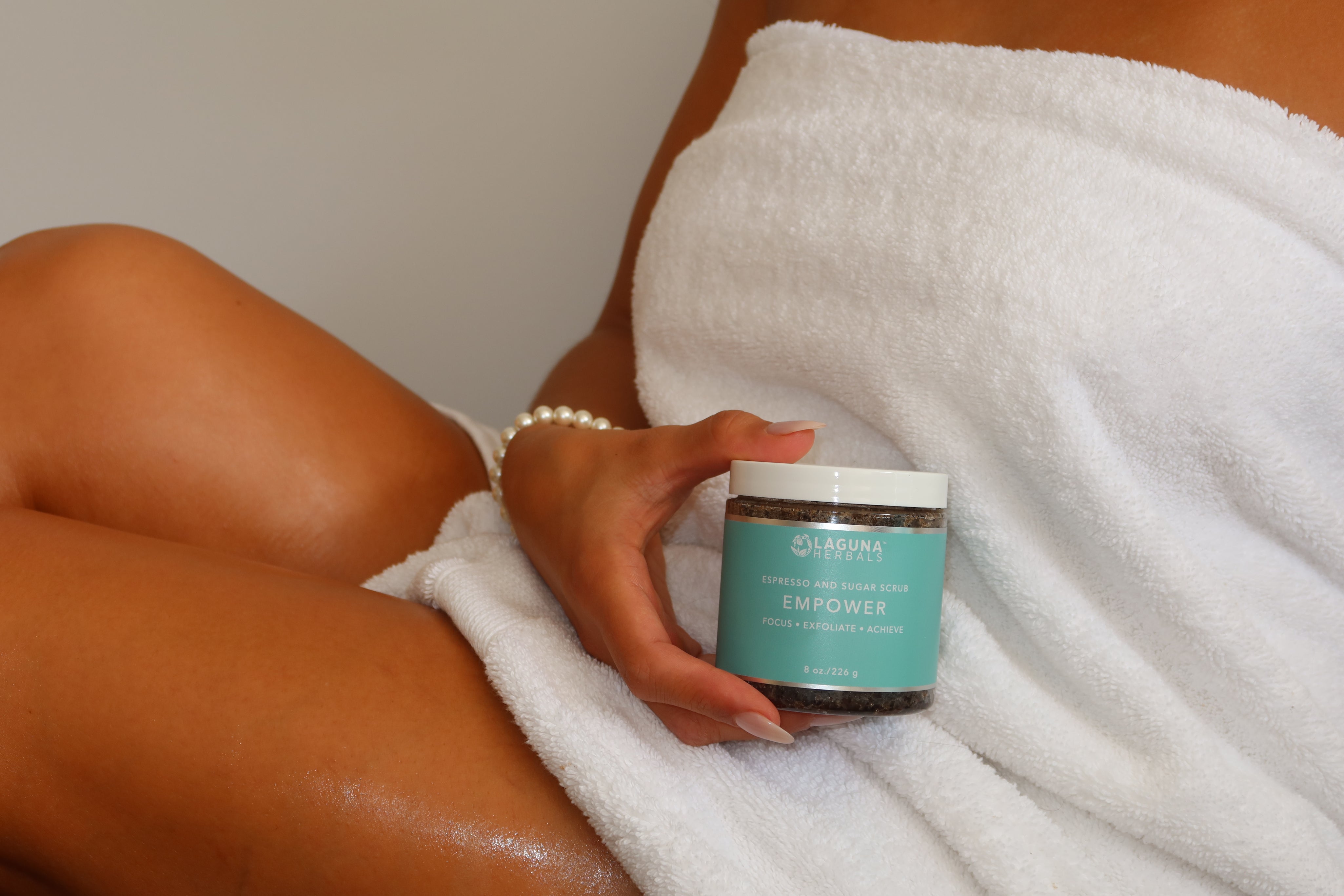 Person holding a jar of skincare product with a towel wrapped around them