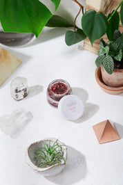 opened Organic Coconut Lip Scrub product image birds eye view in white marble aesthetic backdrop with crystals and green leaves