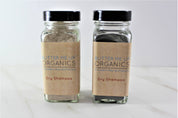 Two Natural Organic Dry Shampoo glass bottles in cute tin packaging with white backdrop close up shot