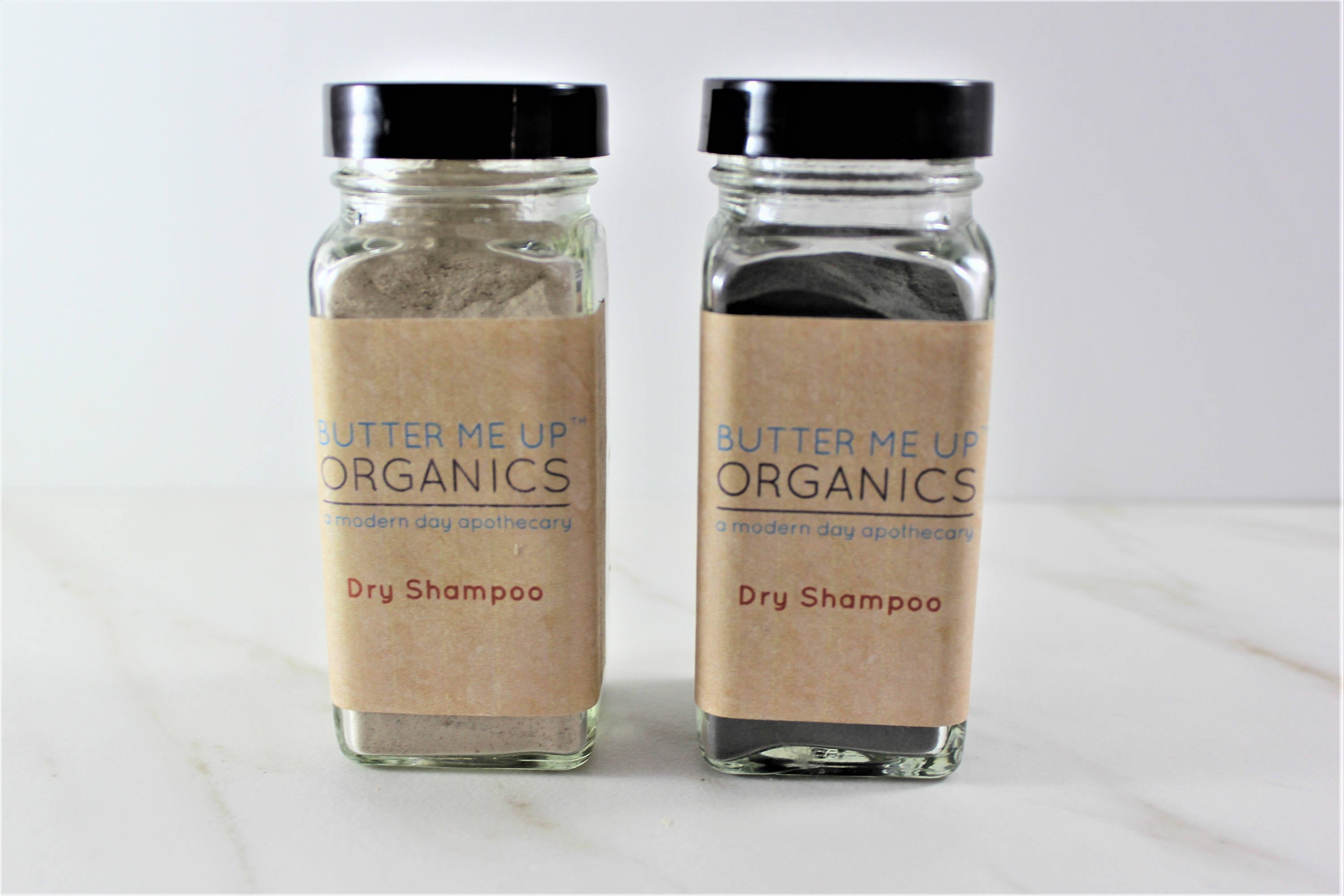 Two Natural Organic Dry Shampoo glass bottles in cute tin packaging with white backdrop close up shot