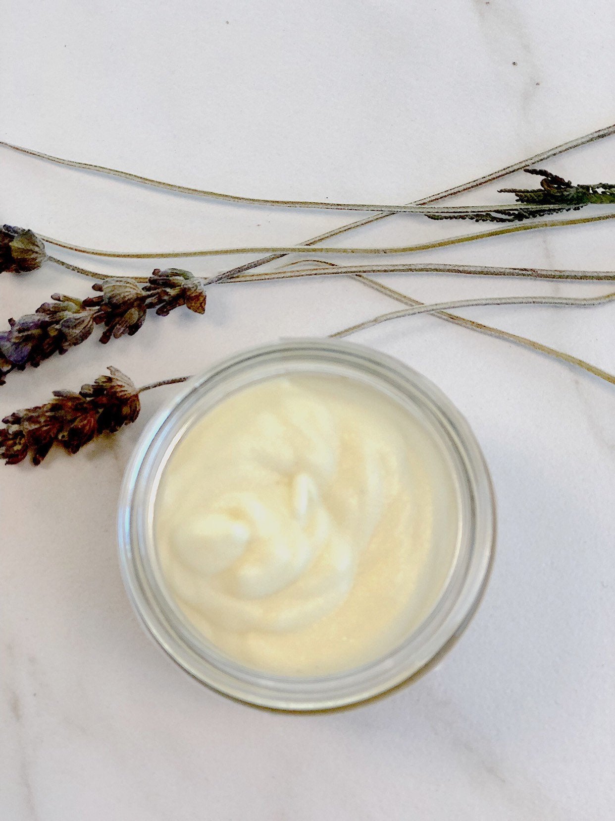opened up Organic Hydrating Facial Moisturizer with Aloe & Rosehip Oil  birds eye view product image in aesthetic kitchen top white backdrop with lavender leaves for decoration