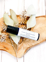 product image birds eye view of Organic Caffeine Eye Repair Serum in aesthetic wooden bark backdrop and sage green leaves